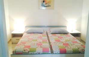 Un lit double avec une courtepointe à motifs floraux, deux tables de chevet et un tableau au mur.