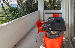 Un balcon agrémenté d’une table et de chaises, entouré de verdure.