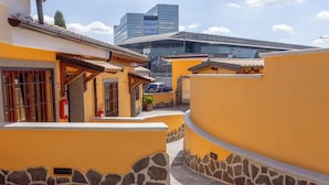 A narrow street with yellow buildings, stone walls, and a modern building in the background. - Il Piccolo Borghetto - Guest House Stazione Tiburtina (Roma)