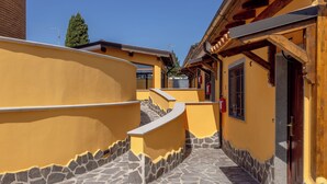 A narrow stone-paved alleyway with yellow walls and wooden beams, leading to a building with a dark wooden door. - Il Piccolo Borghetto - Guest House Stazione Tiburtina (Roma)