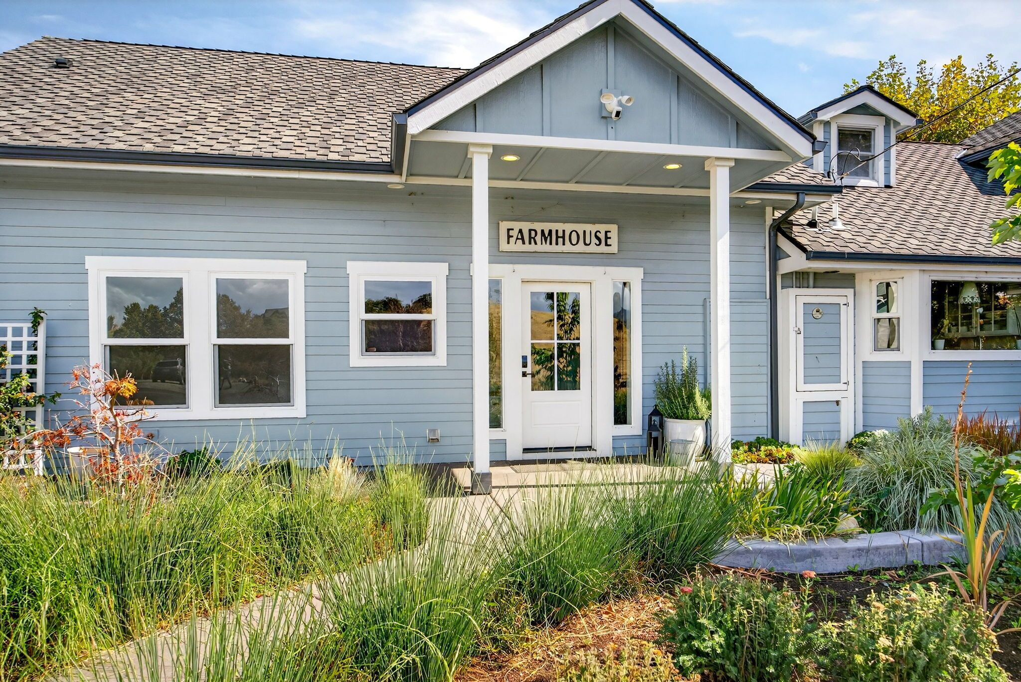 A farmhouse with a covered porch, a front door, and a sign that reads 'FARMHOUSE'.