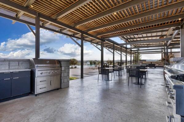 An outdoor patio with a barbecue area, tables, and chairs. - Blue Terrace | Covered Porch, Loft Bedroom, Grill (Fredericksburg)