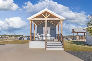 A covered outdoor area with a wooden structure, a door labeled '183', and a small patio with chairs.