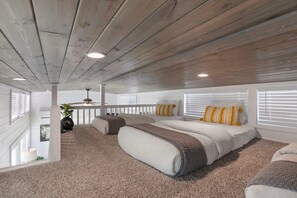 A bedroom with a wooden ceiling, a bed with pillows, a white railing, and a window with blinds.