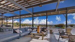 An outdoor seating area with a pool, lounge chairs, and a barbecue setup.