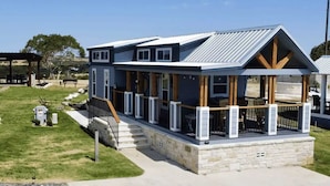 Ein modernes, zweistöckiges Haus mit überdachter Veranda und Steinfundament.