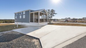A modern two-story house with a covered porch, a driveway, and a clear sky. - Grace's Joy | 2 Bedrooms + Loft | Electric Fireplace (Fredericksburg)