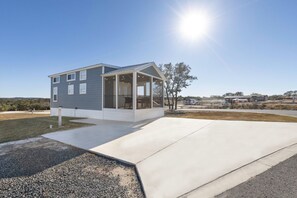 A modern two-story house with a covered porch, a driveway, and a clear sky. - Grace's Joy | 2 Bedrooms + Loft | Electric Fireplace (Fredericksburg)