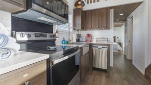 A modern kitchen with stainless steel appliances, wooden cabinets, and a built-in dishwasher. - Grace's Joy | 2 Bedrooms + Loft | Electric Fireplace (Fredericksburg)