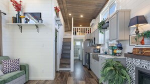 Une cuisine spacieuse avec des meubles blancs, un îlot central et un escalier menant à l’étage supérieur.