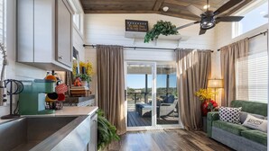Une cuisine moderne dotée d’un four encastré, un coin repas avec un canapé vert et une table, et un balcon offrant une vue agréable.