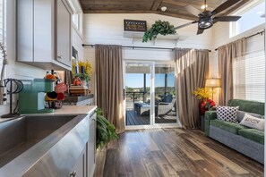 Eine moderne Küche mit Backofen, ein Essbereich mit einem grünen Sofa und einem Tisch sowie ein Balkon mit Blick.