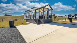 A modern house with a covered porch, a concrete driveway, and a grassy area. - The Geode (Fredericksburg)