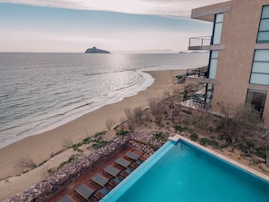 A beachfront hotel with a swimming pool, a beach, and a view of the sea.