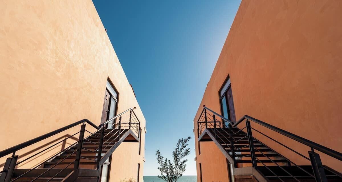 A view of a building with two staircases leading to a window, with a clear sky above.