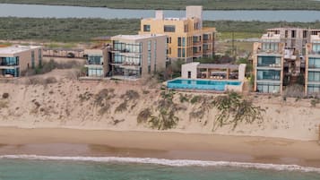A coastal property with multiple buildings, a swimming pool, and a beach.