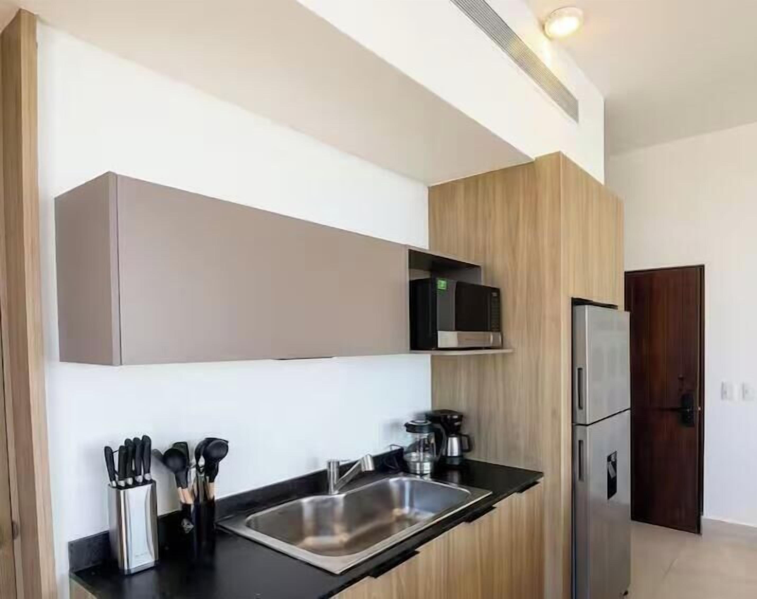 Een moderne keuken met een RVS spoelbak, een magnetron en een koelkast.