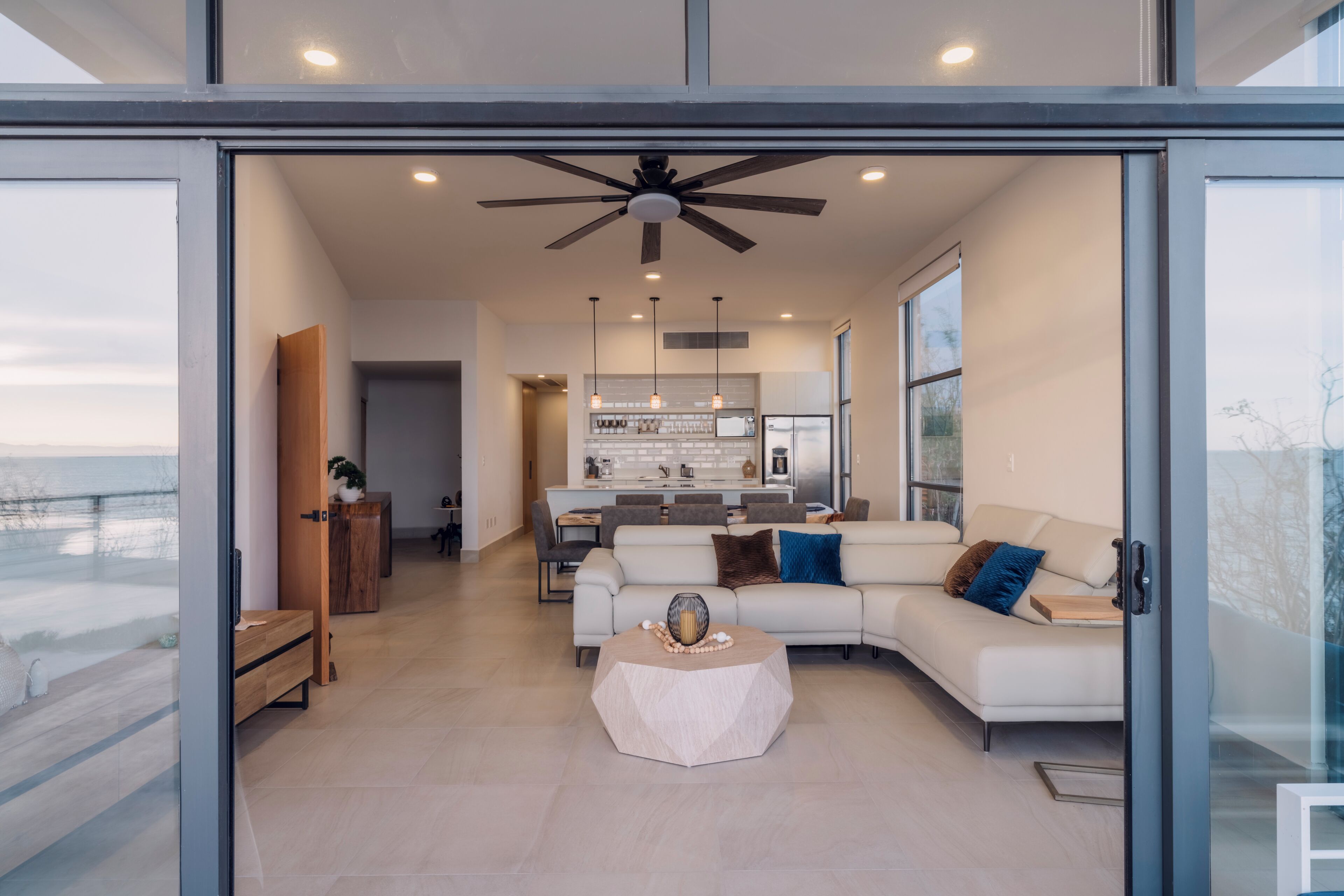 A modern living room with a white sofa, a coffee table, and a ceiling fan.