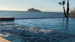 A pool with clear water, a distant island, and two palm trees.