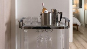 A bar area with a clear glass cart, a bottle of champagne, and wine glasses.