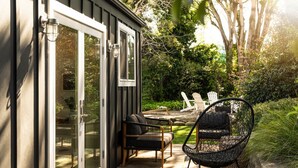 A patio with outdoor furniture, a glass door entrance, and a garden area with trees and shrubs.