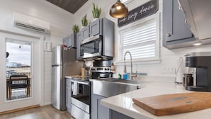 A modern kitchen with stainless steel appliances, grey cabinetry, and a large island. - Then Sings My Soul | Covered Porch & Fireplace! (Fredericksburg)