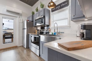 A modern kitchen with stainless steel appliances, grey cabinetry, and a large island. - Then Sings My Soul (Fredericksburg)