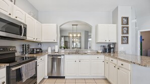 Een moderne keuken met witte kasten, roestvrijstalen apparatuur en een granieten aanrecht.