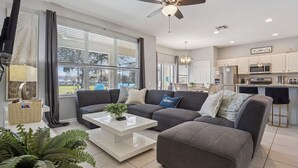 Een moderne woonkamer met een grijze modulaire bank, een witte salontafel en een plafondventilator.