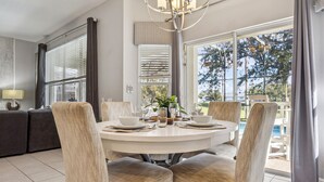 Een eetgedeelte met een ronde tafel, zes stoelen en uitzicht op de omgeving.