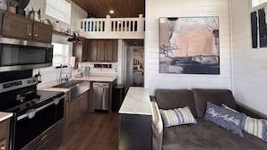A compact kitchen with modern appliances, a dining area with a couch, and a loft bedroom with a balcony. - Comfortably Numb 223 (Fredericksburg)
