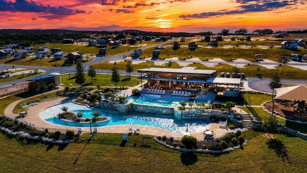 A resort with a large pool, a covered area, and a view of the sunset. - Comfortably Numb 223 (Fredericksburg)