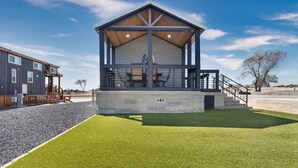 A modern building with a covered porch, stone steps, and a sign reading 'RITZ'. - Tiny Treasure | 1.5 Baths | Sleeps 6 | Dual Porches (Fredericksburg)
