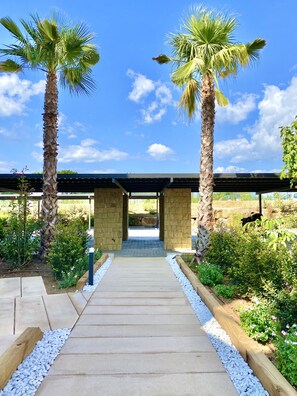 A pathway leading to a covered structure with stone pillars, surrounded by greenery and palm trees. - 23 - Apt. in la Cala Golf (La Cala de Mijas)
