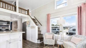 Een ruime keuken met moderne apparatuur, een houten trap en een gezellige zithoek met bloemrijk gestoffeerde stoelen.