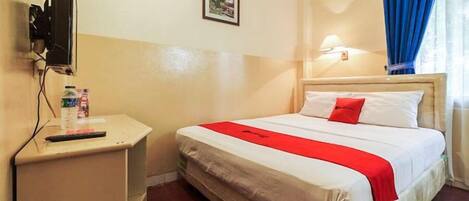 A hotel room with a bed, a bedside table, a television, and a wall-mounted light.