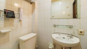 Casa de banho com sanita, lavatório, espelho e porta-toalhas.