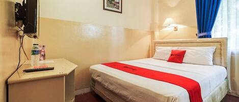 A hotel room with a bed, a TV on a stand, a small table with a remote, and a picture on the wall.