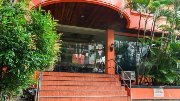 Um edifício com uma entrada curva, uma escadaria que leva à entrada e uma placa na parede.