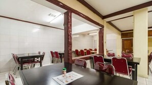 Uma sala de conferência com uma mesa grande, cadeiras vermelhas e um quadro branco.
