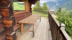 Eine Holzhütte mit einer Terrasse, einer Bank und einem Tisch.