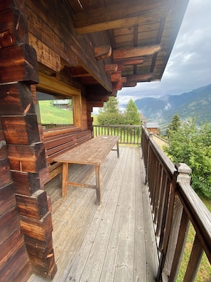 A wooden cabin with a deck, a bench, and a table. - Chalet Hauteluce Les Saisies with sauna for 10 people (Hauteluce)