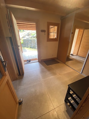 A room with a tiled floor, a wooden door, a small window, and a view of the outside. - Chalet Hauteluce Les Saisies with sauna for 10 people (Hauteluce)