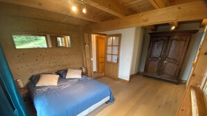 Ein Schlafzimmer mit Holzboden, einem Bett, einem Kleiderschrank und einem Fenster.