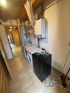 A laundry area with a washing machine, dryer, and a small black refrigerator. - Chalet Hauteluce Les Saisies with sauna for 10 people (Hauteluce)