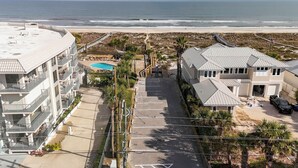 Zona residencial costera con piscina, playa y un edificio de varios pisos con balcones.