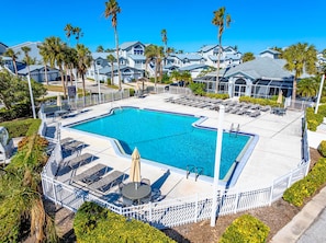 A large outdoor swimming pool surrounded by lounge chairs and umbrellas, with palm trees and a row of houses in the background. - Spacious 1st-Floor Siesta Key Condo by #1 Beach (Siesta Key)