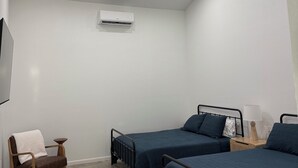 Une chambre avec deux lits, un ventilateur de plafond, un appareil de climatisation et une fenêtre.