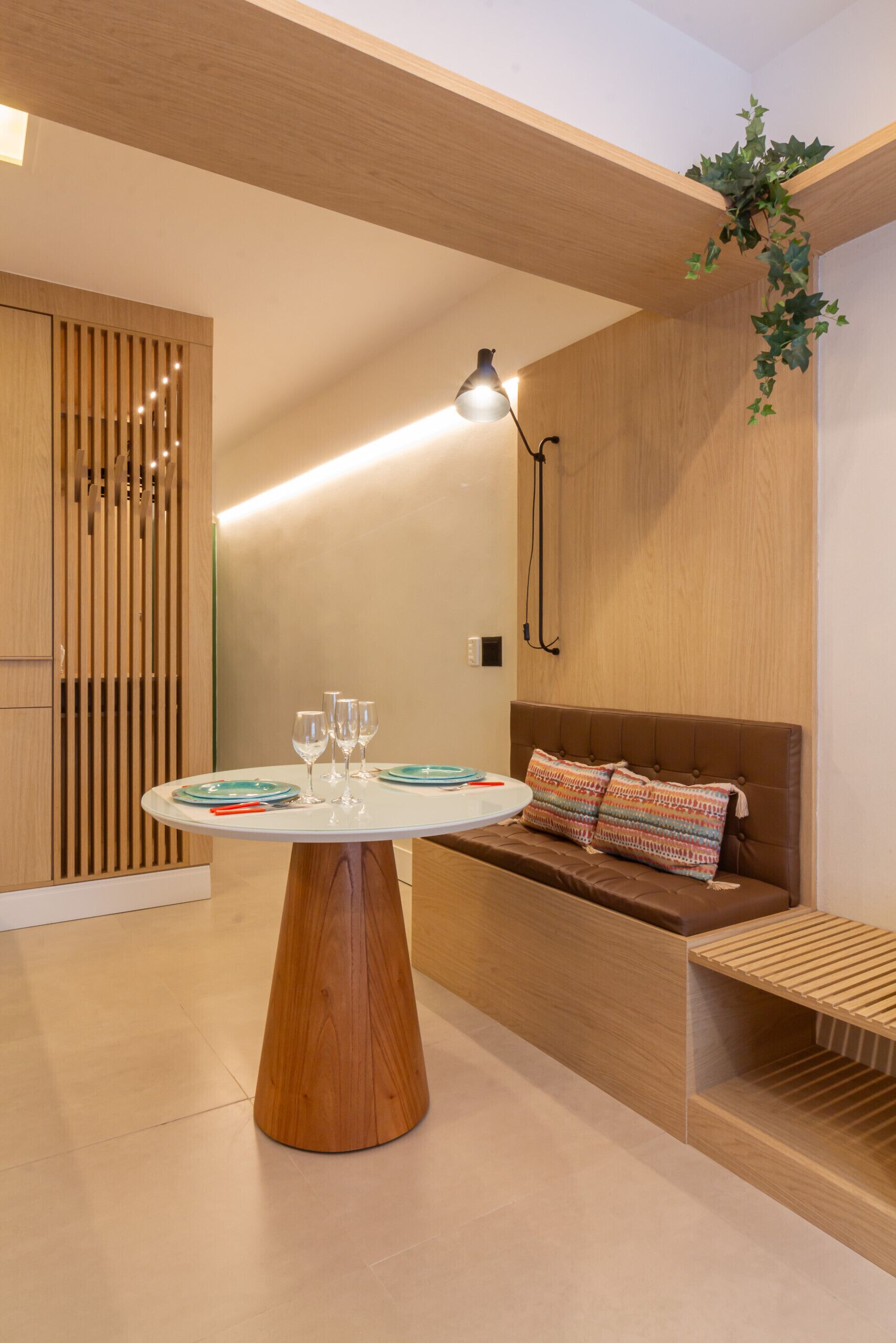A modern room with a round wooden table, a brown sofa, and a wooden slatted bench.