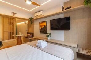 A modern hotel room with a large bed, a flat-screen TV, a ceiling fan, and a small table with glasses and a menu. - Incredible Studio in Copacabana - CR703 (Rio de Janeiro)